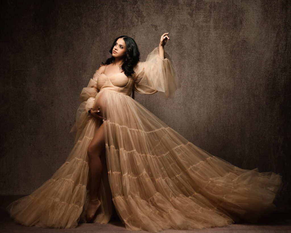 Pregnant woman wearing tulle maternity gown on a brown textured backdrop. Studio maternity photographer in Marietta Georgia. 