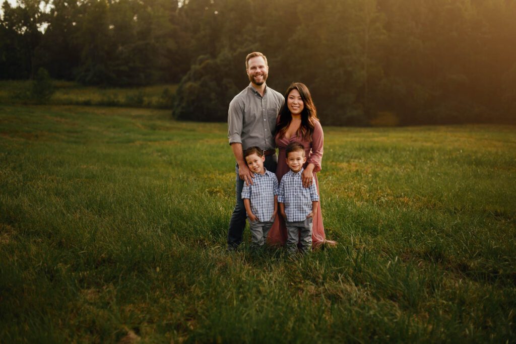family of four standing closely together in a field of grass at Garrard Landing Park.
