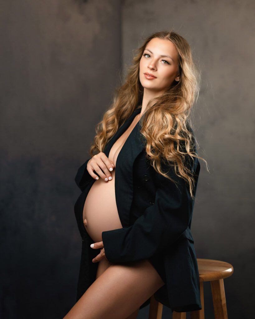Maternity portrait in an open black blazer by an Alpharetta maternity photographer against a dark studio backdrop.