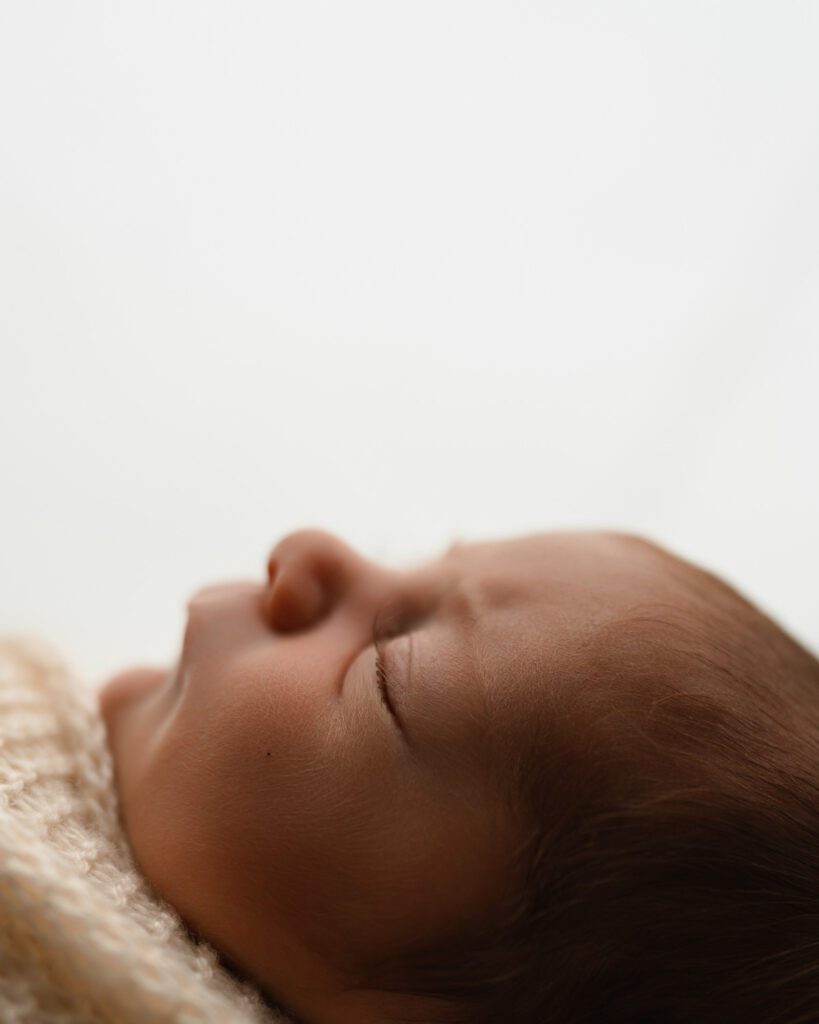 Side-profile close-up of a sleeping newborn baby showing fine eyelashes and hair during Alpharetta newborn photography.