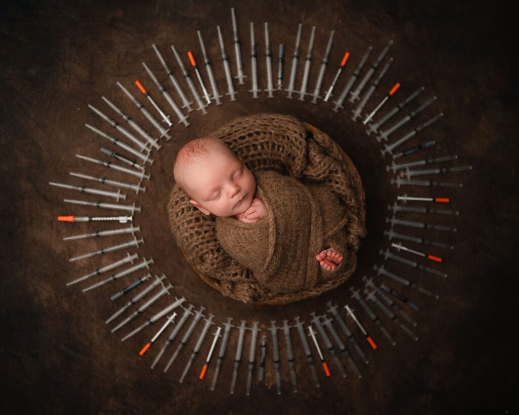 Atlanta IVF newborn portrait of a sleeping baby boy in a wooden bowl surrounded by circle of IVF syringes.
