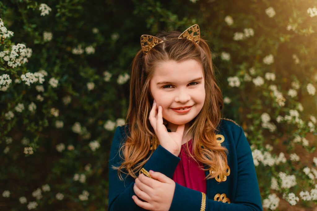 tween girl wearing cat ear headband with hand on her chin smiling