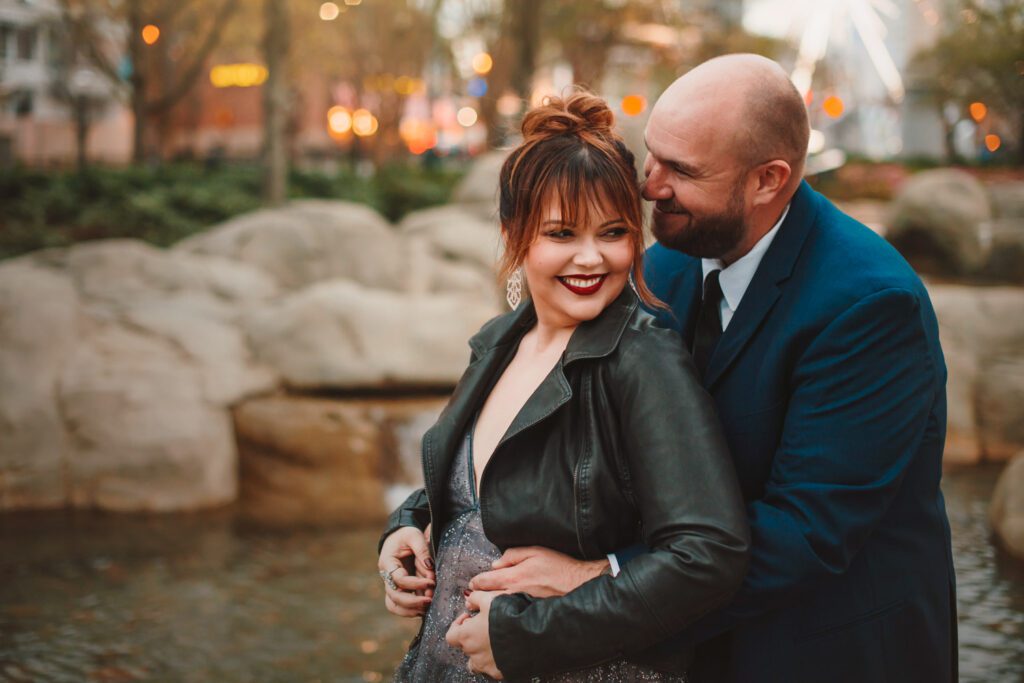smiling parents hug and laugh in front of water gardens in Five Quilts plaza in Atlanta