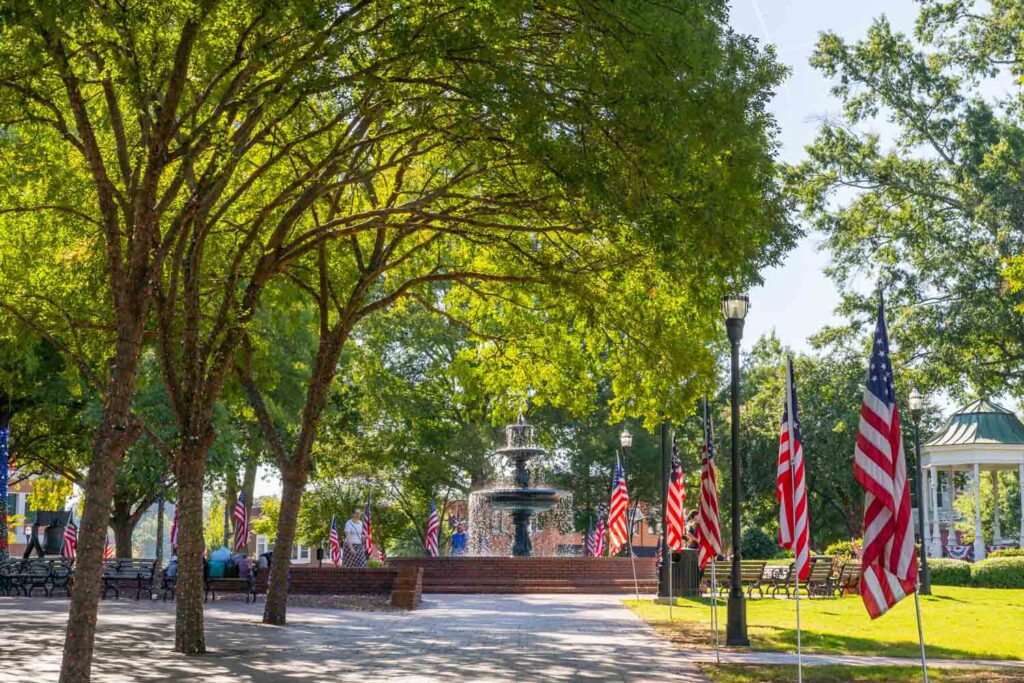 Cast iron fountain framed by American flags and shady trees in Glover Park at Marietta Square, GA.