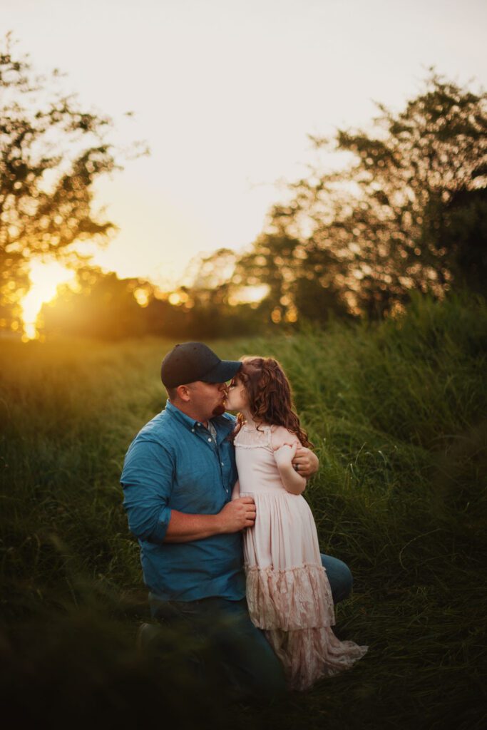 Dad kneeling to hug his daughter in the Cheatham Hill meadows at Kennesaw Mountain in Marietta, GA