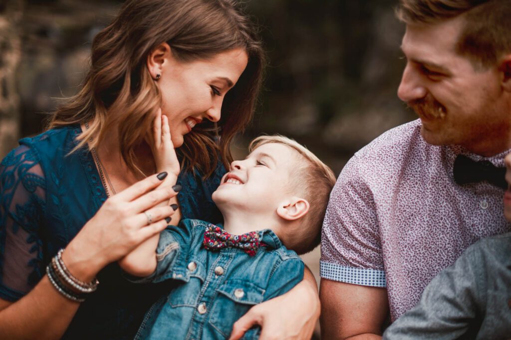 Mom laughing with her young son while dad smiles beside them in a close family moment.