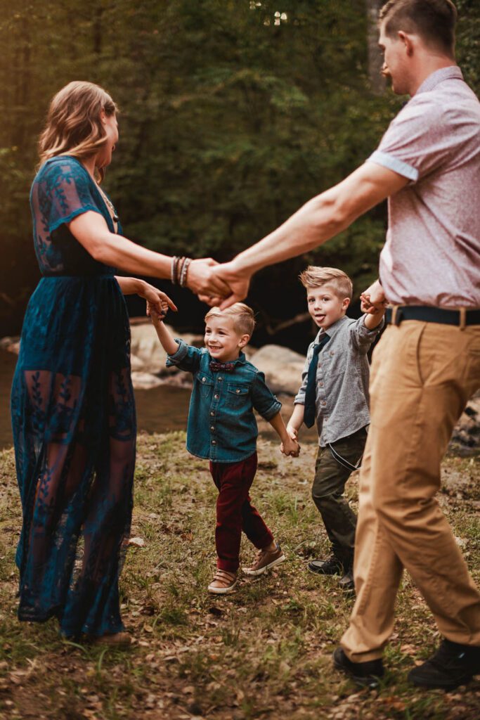 Family holding hands beside a rocky creek with the old Cochran Mill ruins in the background