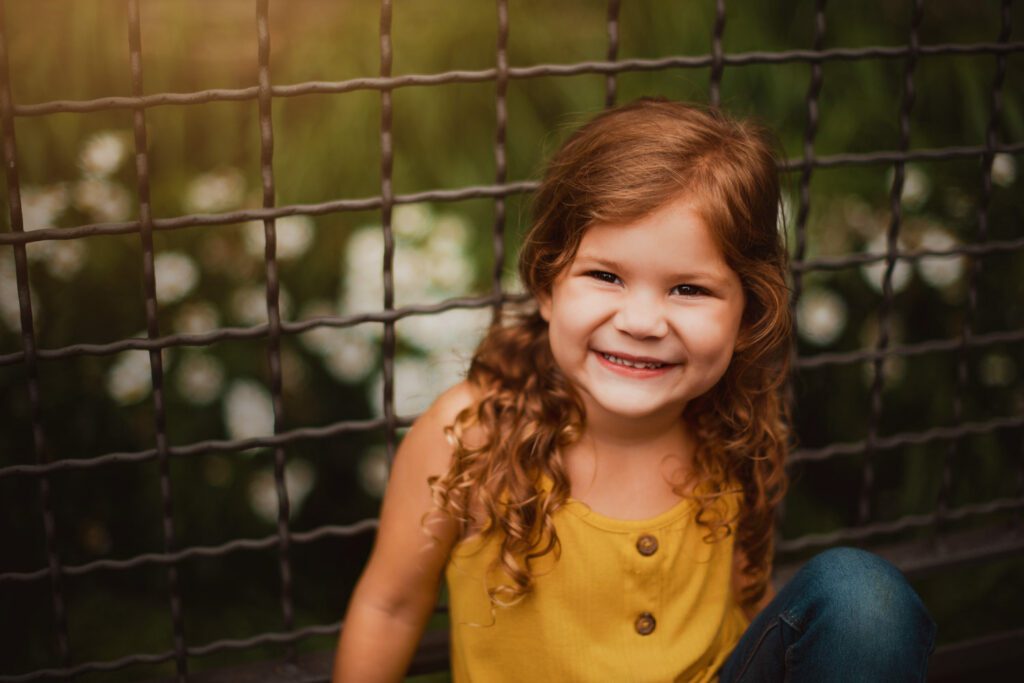 Smiling daughter beside industrial fencing along the Atlanta BeltLine Eastside Trail near Ponce City Market.