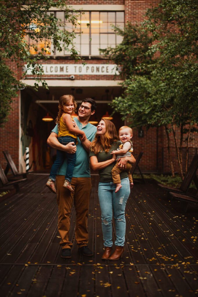 A family strolls along the BeltLine bridge at Ponce City Market near the retro 'Welcome to Ponce' marquee sign in Atlanta, Georgia.