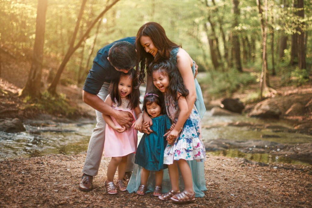 family of five hugging while standing in Vickery Creek Park at sunset in Roswell, GA
