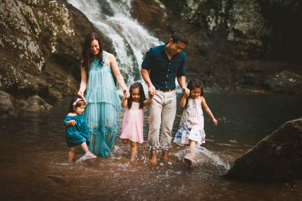 family wading through the water with the Roswell Mill waterfall in the background in Roswell, GA