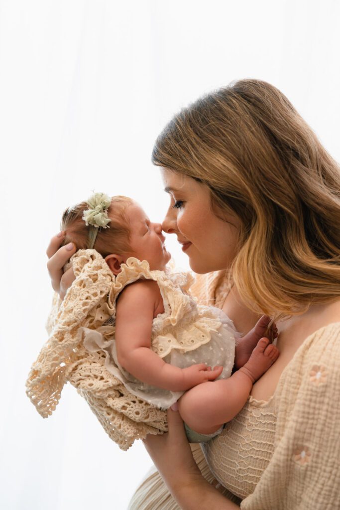 Mom touches noses with her newborn daughter against a bright window for a Sandy Springs newborn photographer.