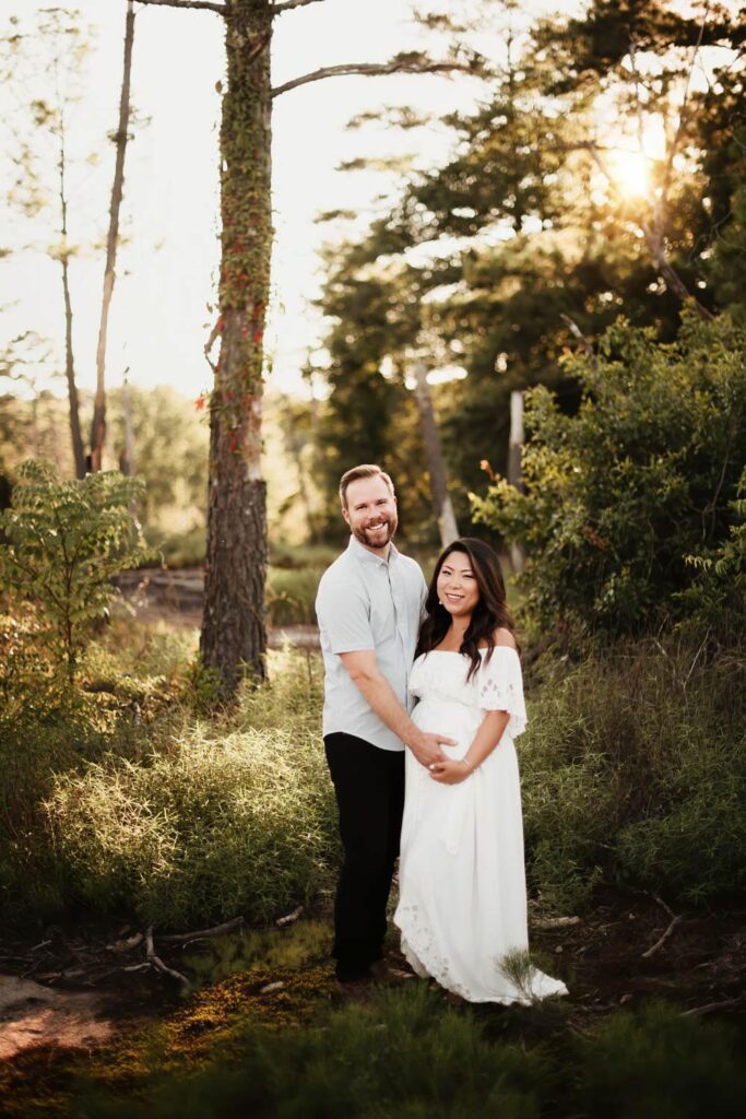 expecting couple standing close together among trees during a golden-hour maternity session at Arabia Mountain.