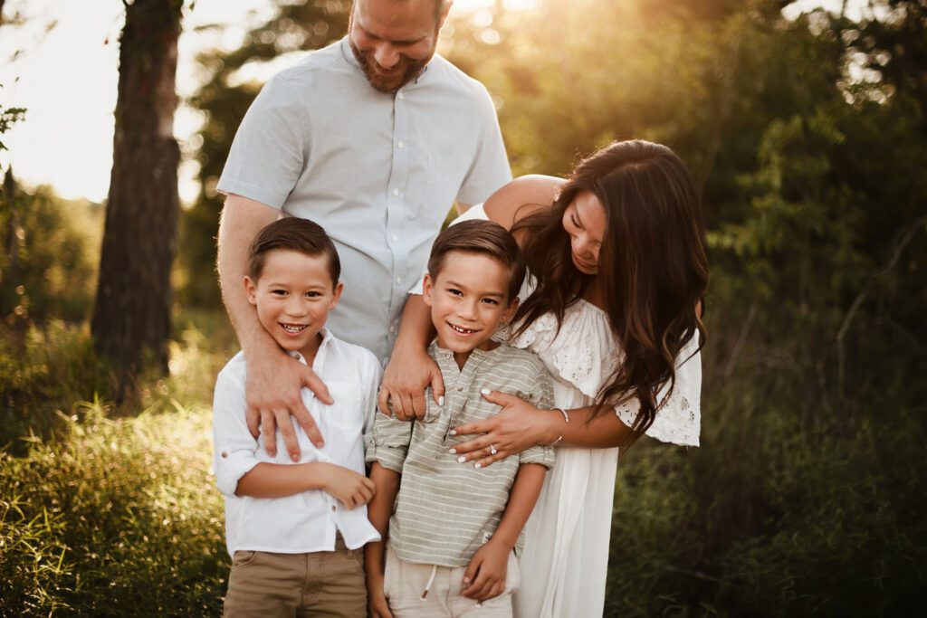 One brother is wearing a white shirt with khaki shorts as his twin wears a green and white striped shirt and parents match. 